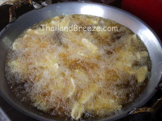 Deep frying Thai bananas until they turn golden brown.