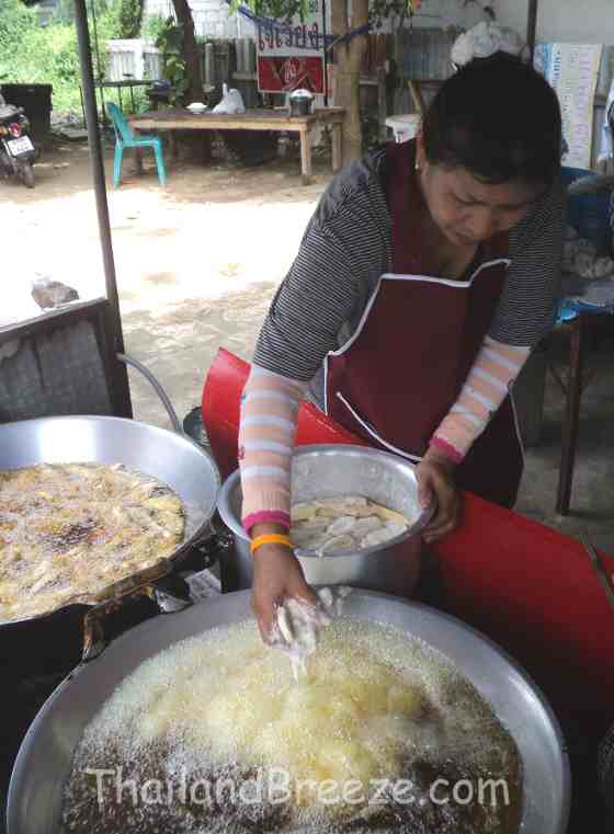 Putting the battered bananas in the boiling oil to make deep fried bananas.