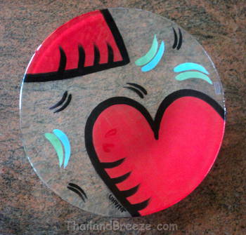 A Swedish Kosta Boda glass dish with a red heart design.