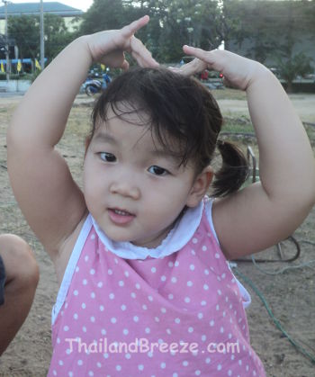 A young Thai girl making the sarang hae yo gesture to say I love you.